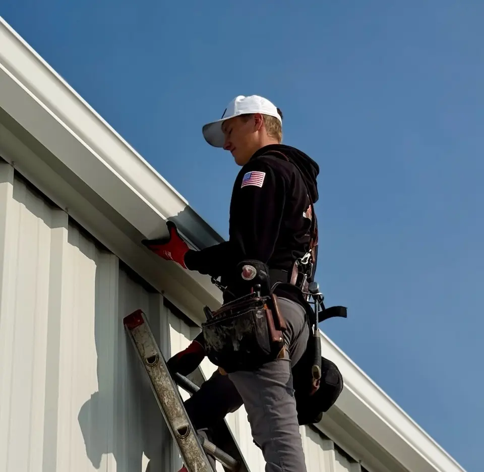 Installer fastening seamless gutter at the fascia