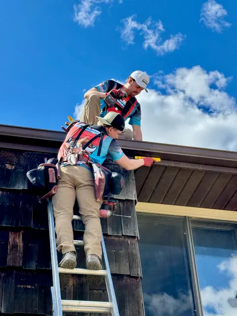 Installer working a gutter run beside an upper window